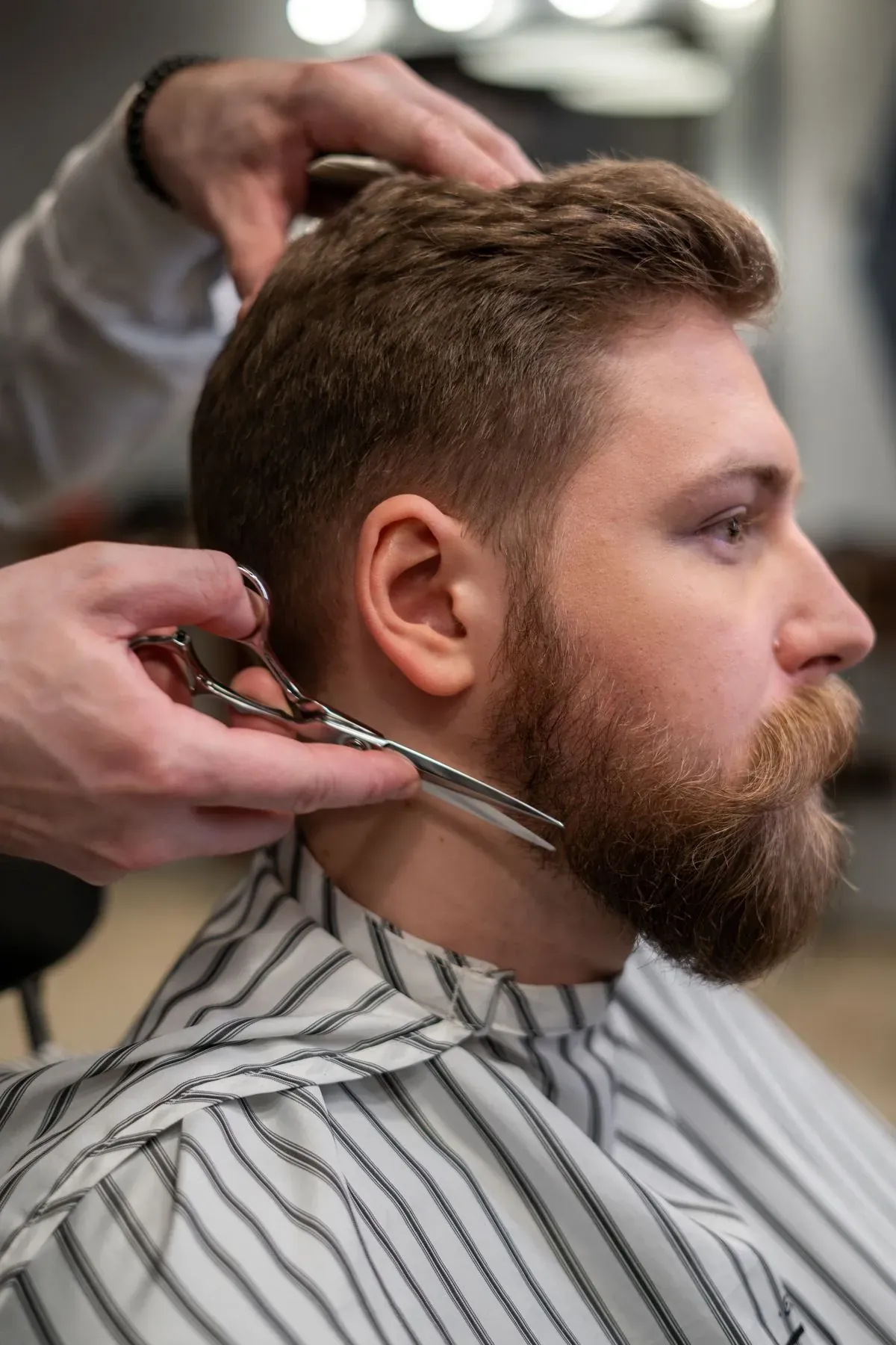 Manos de un barbero cortando el pelo con tijera, de cerca